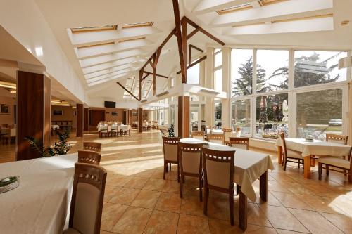 BáčKlaudia's Hotel & Restaurant at Golf Resort, Bač Šamorín的用餐室设有桌椅和窗户。