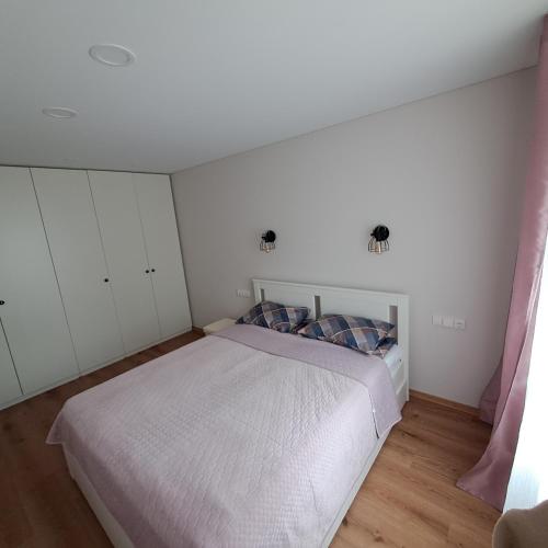 考纳斯Vytės apartamentai的卧室配有白色的床和白色橱柜。