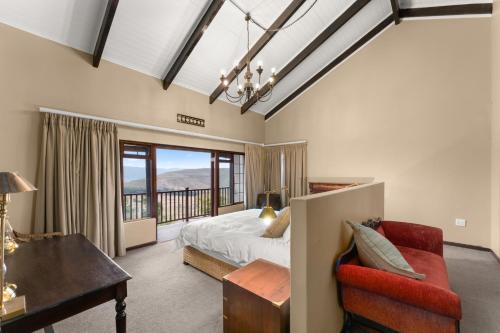 海姆维尔Drakensberg Luxury Accommodation - Misty Ridge的一间卧室配有一张床、一张桌子和一把椅子