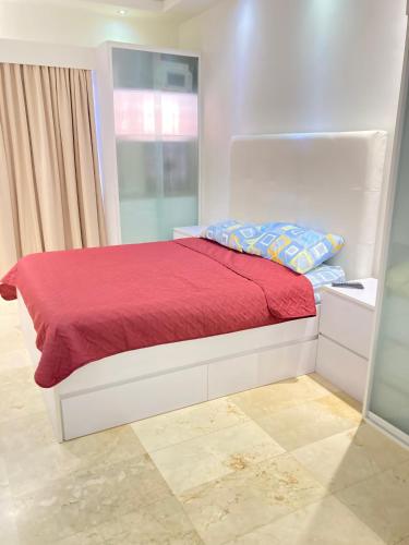 加拉加斯HATILLO SUITE的一张带红色毯子的白色床和窗户