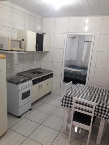 佩尼亚Apartamentos C. Santos的白色的厨房配有炉灶、桌子和微波炉。