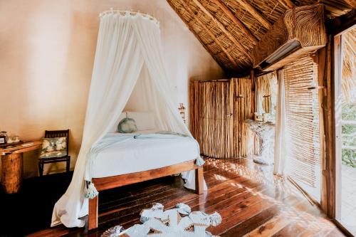 图卢姆阿祖里克度假酒店的一间卧室配有一张带蚊帐的床