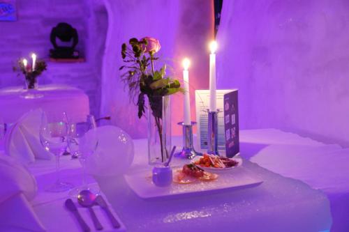 克尔茨什瓦拉乡Hotel of Ice Transylvania的紫色客房内的一张带蜡烛和鲜花的桌子