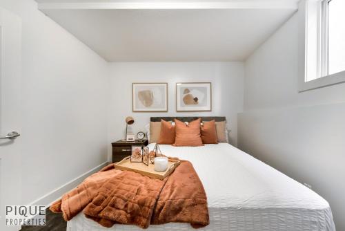 埃德蒙顿Stunning Modern Suite - King Bed - Free Parking & Netflix - Fast Wi-Fi - Long Stays Welcome的白色卧室配有带橙色毯子的床