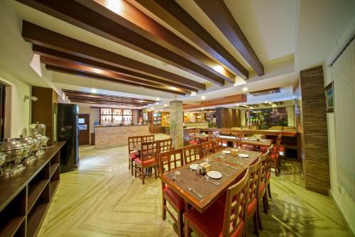 博卡拉库玛里斯塔酒店 的一间带木桌椅的餐厅和一间酒吧