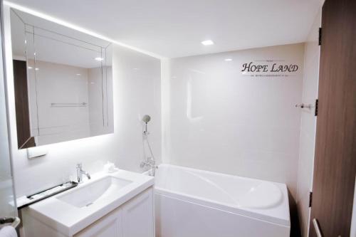 曼谷素坤逸路8号希望之地酒店的白色的浴室设有水槽和镜子