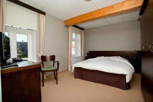 赖皮纳拉匹纳酒店的一间卧室配有一张床、一张书桌和一台电视