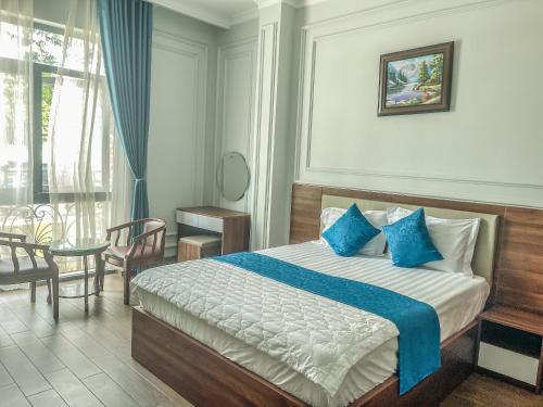 Bến CátKhách sạn Hoàng Minh Châu Mỹ Phước的一间卧室配有一张带蓝色枕头的床