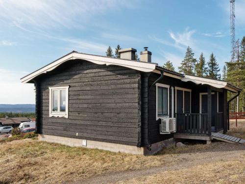 Kopparberg6 person holiday home in KOPPARBERG的坐在田野顶上的一间黑色小房子