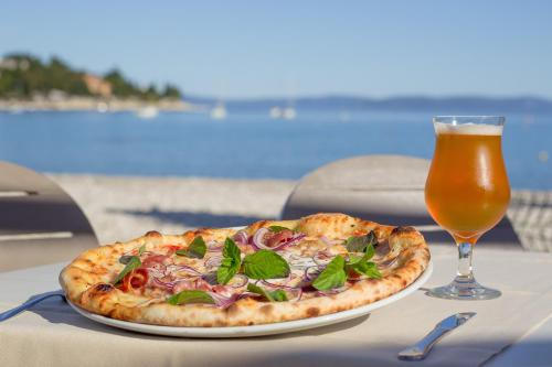 拉巴克纳西斯酒店 - 玛斯林尼卡酒店及度假村的一杯啤酒旁的一张桌子上的比萨饼