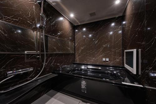 相模原市BAMBOO GARDEN 相模原的浴室设有黑色大理石墙壁和淋浴。