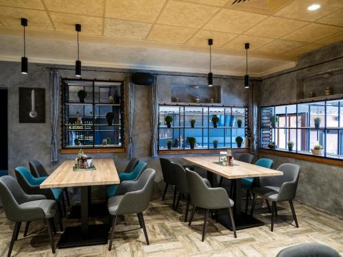 Pernik埃立特酒店的餐厅设有2张桌子和椅子以及窗户。