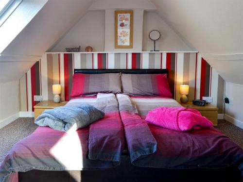 班夫Coldhome Cottage的一间卧室配有一张带紫色枕头的大床