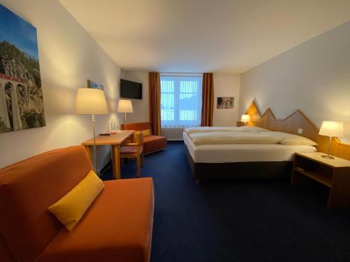 贝尔金Hotel Weisses Kreuz Bergün的酒店客房,设有两张床和一张沙发
