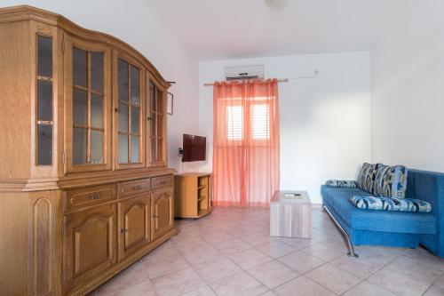 普利拉卡Apartments Sunset -near Queen Beach的客厅配有蓝色的沙发和大型木制橱柜。