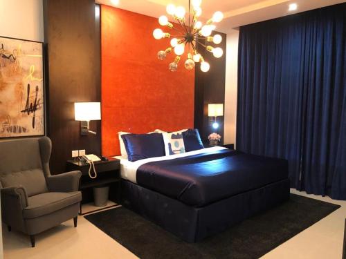 利雅德Dana Hotel & Residences 2的一间卧室配有一张床、一把椅子和一个吊灯。