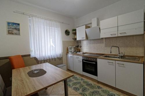 希洛App2 Marin的厨房配有白色橱柜和木桌