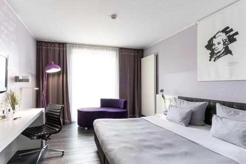 沃尔芬比特尔elaya hotel wolfenbuettel ehemals Rilano 24 7 Hotel Wolfenbüttel的酒店客房,配有一张床、一张桌子和椅子