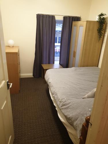 阿什顿下安林恩2 bedroom apartment in Greater Manchester的一间卧室配有一张床、一张桌子和一个窗户。