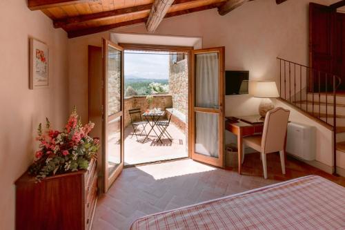 皮恩扎博尔戈圣特安布罗吉奥度假村的一间带书桌的卧室和一间带阳台的客房