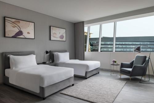多哈Steigenberger Residence Doha的酒店客房,配有两张床和椅子