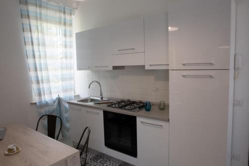 维罗纳Mercante In Fiera的厨房配有白色橱柜、水槽和炉灶。