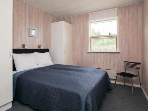 伦斯楚普Holiday home Hjørring IV的一间卧室设有一张床、一个窗口和一把椅子