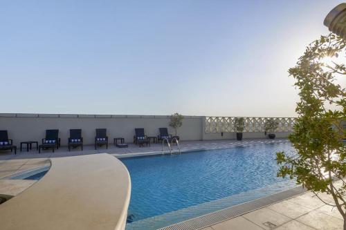 多哈萨菲尔多哈酒店的大楼内带蓝色椅子的大型游泳池