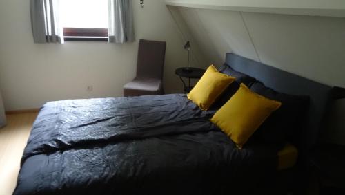拉纳肯Chalet met wellness的一间卧室配有一张带两个黄色枕头的床