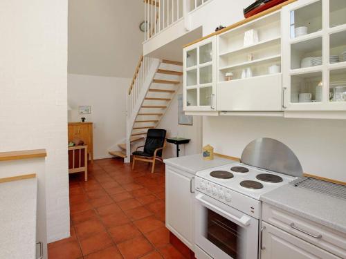 布拉万德4 person holiday home in Bl vand的一间带白色炉灶和楼梯的厨房