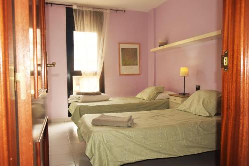 厄尔梅达诺alquilaencanarias Duplex beach Cabezo terrace and pool的配有粉红色墙壁的客房内的两张床