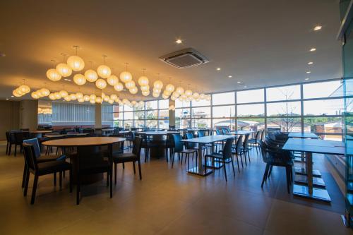 克里西玛Hotel Darolt Criciúma的餐厅设有桌椅和大窗户。