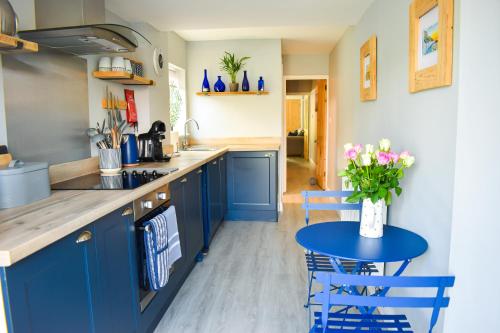 PakefieldSeagull Cottage - Suffolk Coastal Escapes的厨房配有蓝色橱柜和鲜花桌