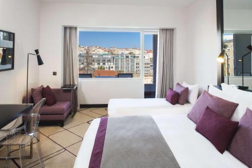 里斯本Avani Avenida Liberdade Lisbon Hotel的酒店客房设有两张床和窗户。