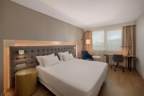 圣艾修伯里新罕布什尔州里昂机场酒店的酒店客房设有一张白色大床和一张书桌