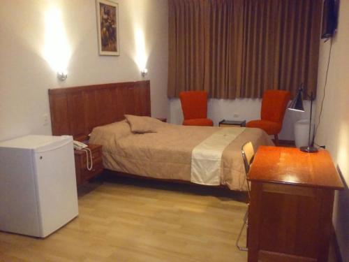 伊基托斯SAFARI HOTEL IQUITOS的酒店客房,配有一张床和两张橙色椅子