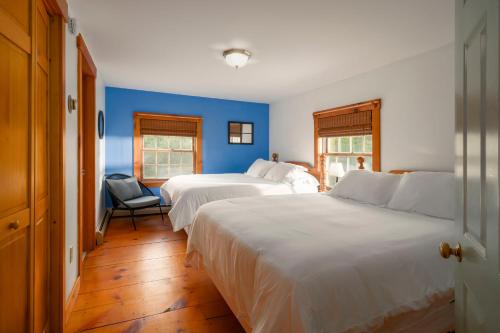 East BurkeColonial Home Directly on Kingdom Trails!的一间卧室设有两张床和蓝色的墙壁