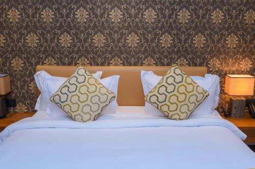 金沙萨AQUA INN Hotel的一张白色的床,上面有两个枕头