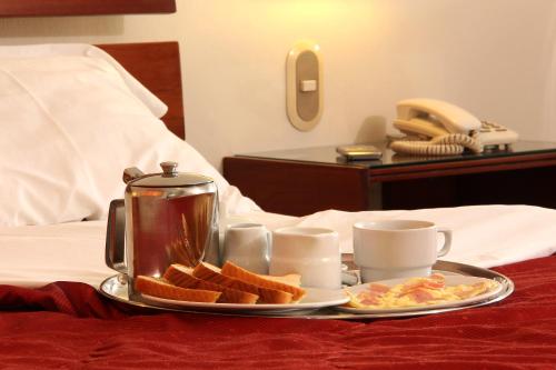 利马Los Mirtos suite & Hotel的床上的早餐盘,包括烤面包和咖啡