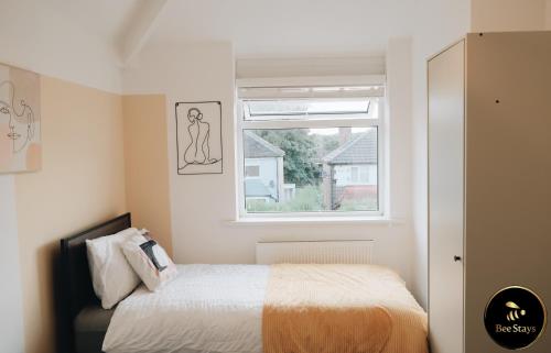 曼彻斯特Bee Stays - Caldecott House的一间卧室设有一张床和一个窗口