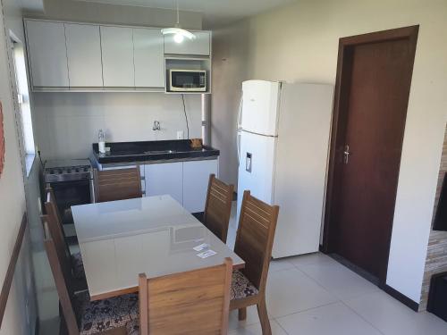 伊塔佩马Duplex com vista do mar!的厨房配有桌子和白色冰箱。