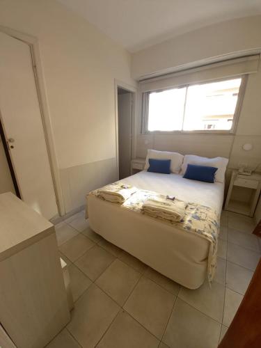 马德普拉塔Hotel Albamar的一间卧室配有一张带蓝色枕头的床和一扇窗户。
