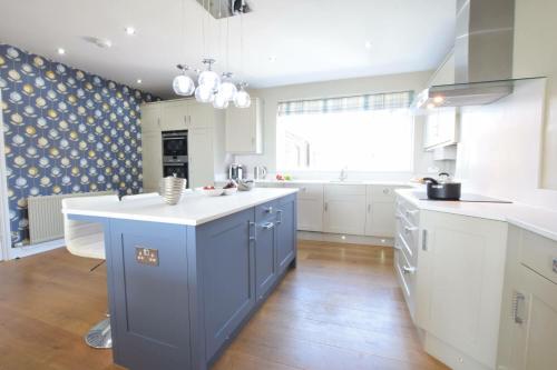 绍斯沃尔德St Marys View, Southwold的厨房配有蓝色和白色的橱柜和大窗户