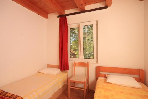 兹曼Secluded fisherman's cottage Krknata, Dugi otok - 397的客房设有两张床、一把椅子和窗户。