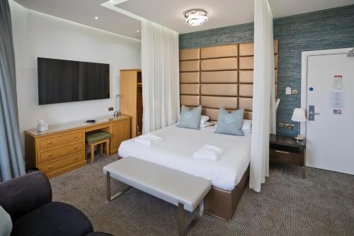 艾尔地平线酒店的一间卧室配有一张床、一张书桌和一台电视。