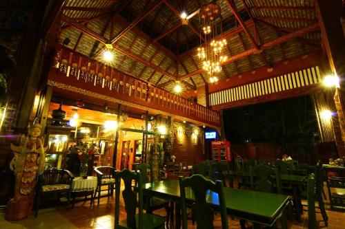 美索伊拉瓦迪度假酒店的一间晚上配有绿色桌椅的餐厅