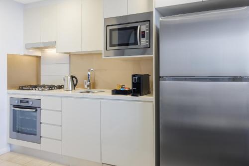 悉尼泽特兰美利通公寓式酒店的厨房配有不锈钢冰箱和微波炉。