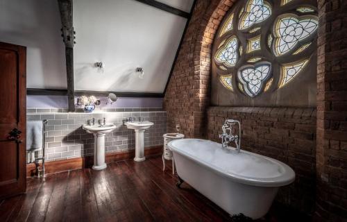 伍斯特Stanbrook Abbey Hotel, Worcester的带浴缸、两个盥洗盆和窗户的浴室