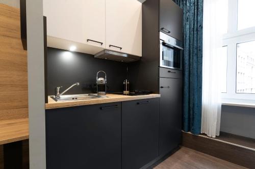 纽伦堡Aparthotel by dasPaul的厨房配有黑色橱柜、水槽和窗户。