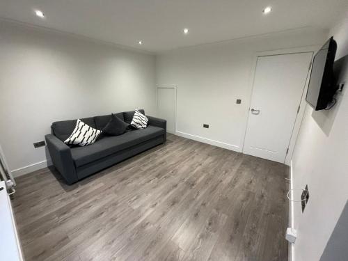 伦敦London West Ham Apartments的客厅配有黑色沙发和电视